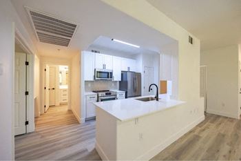 A modern kitchen with a white countertop and wooden flooring.